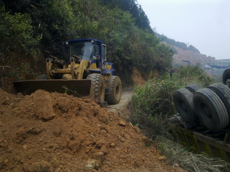 上面的车在清理车内的矿粉，先指挥铲车填土，转盘屁股会碰到山壁